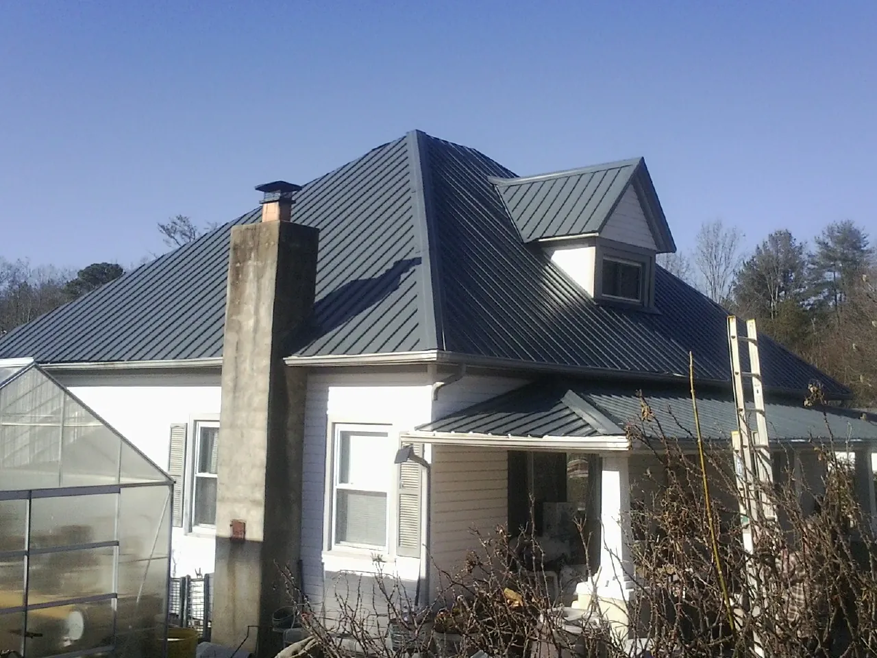Dark blue standing seam metal roof on a white farmhouse with dormer — Slate & Tile Roof Repair by Roofing Brothers in Webster Springs