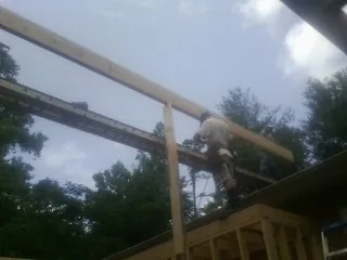 Carpenter setting a ridge beam over a new addition frame — Ice Dam Removal by Roofing Brothers in Webster Springs