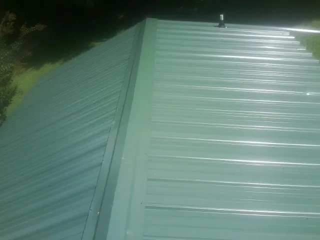 New green metal panels meeting at the ridge of a roof — Flat Roof Repair work by our crew in Webster Springs