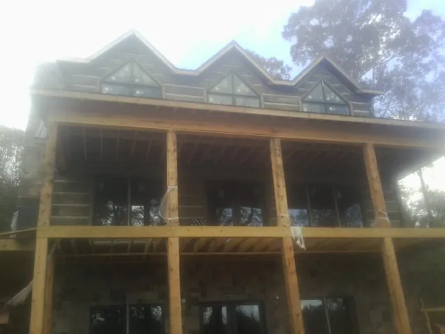 Dormers and porch framing on a large log home under construction — Roof Coating work by our crew in Webster Springs