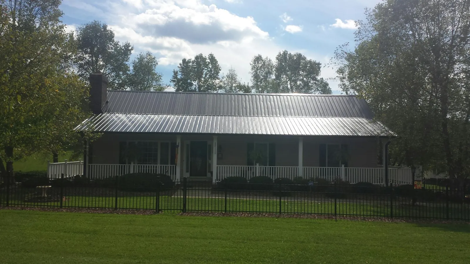 Gray metal roof on a brick ranch with a full width front porch — Gutter Guard Installation work by our crew in Webster Springs