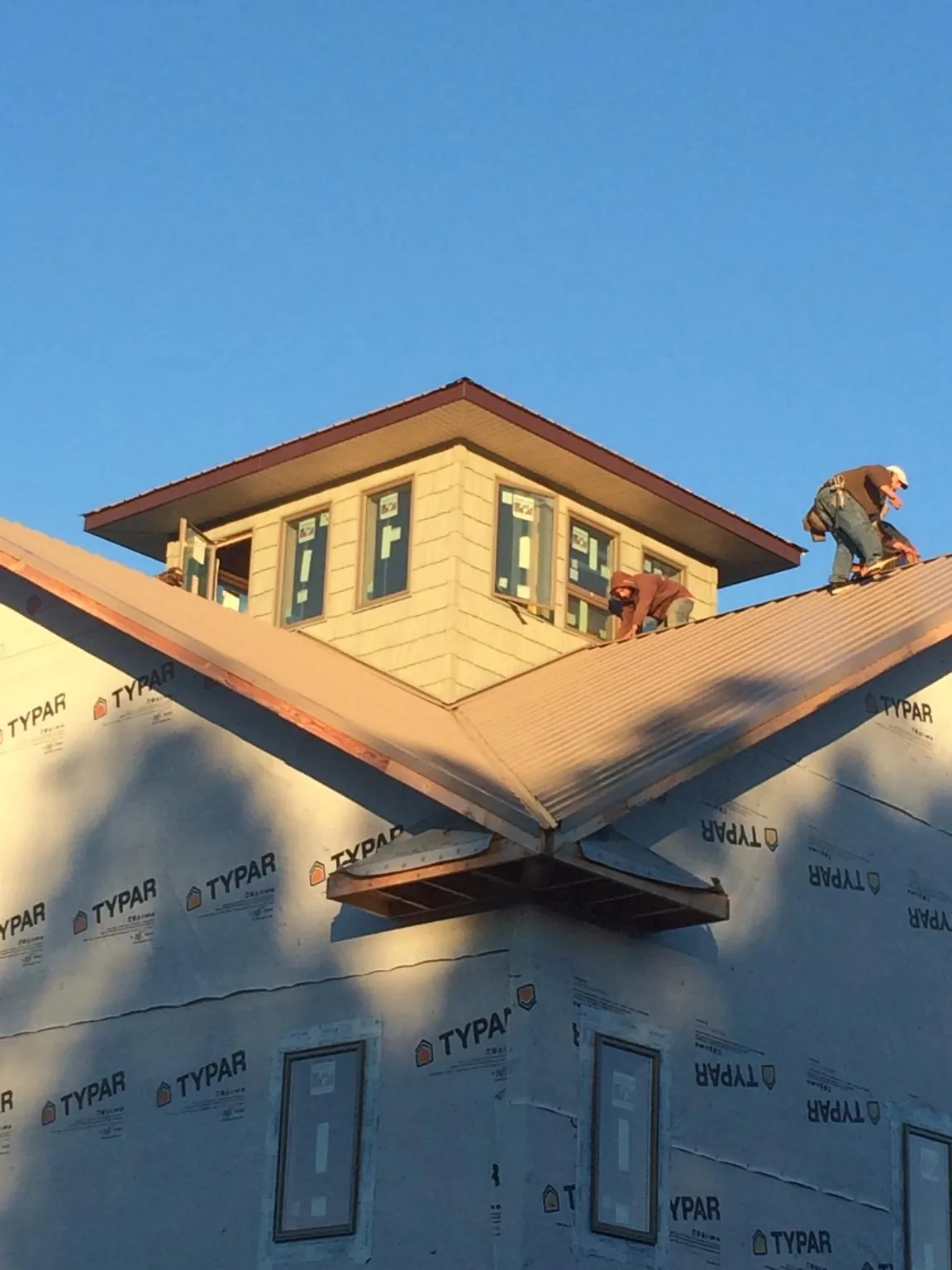 Roofers working around a rooftop cupola on a new metal roof at sunset — Roof Waterproofing in Webster Springs by Roofing Brothers